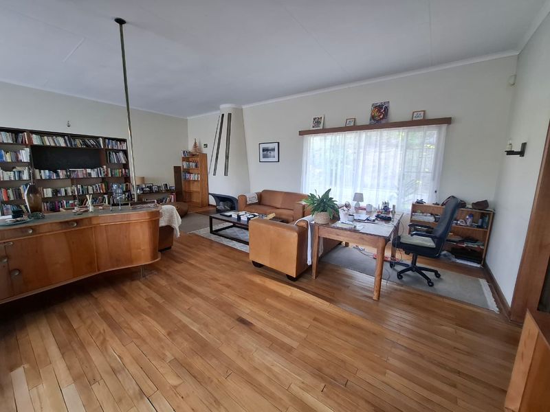 Spacious living room featuring hardwood flooring, a built-in fireplace, and integrated shelving, offering a comfortable and functional layout with ample natural light.