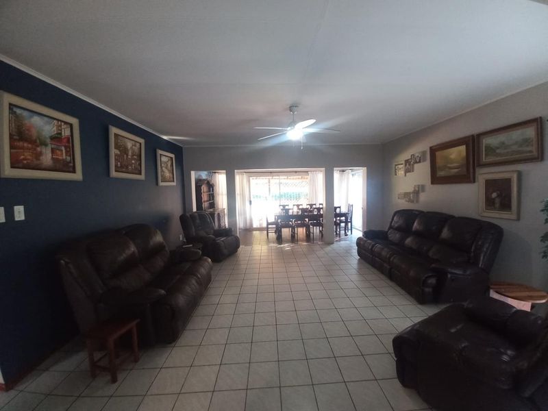 Spacious open-plan living and dining area featuring tiled flooring, a ceiling fan, and sliding glass doors leading to an outdoor space.