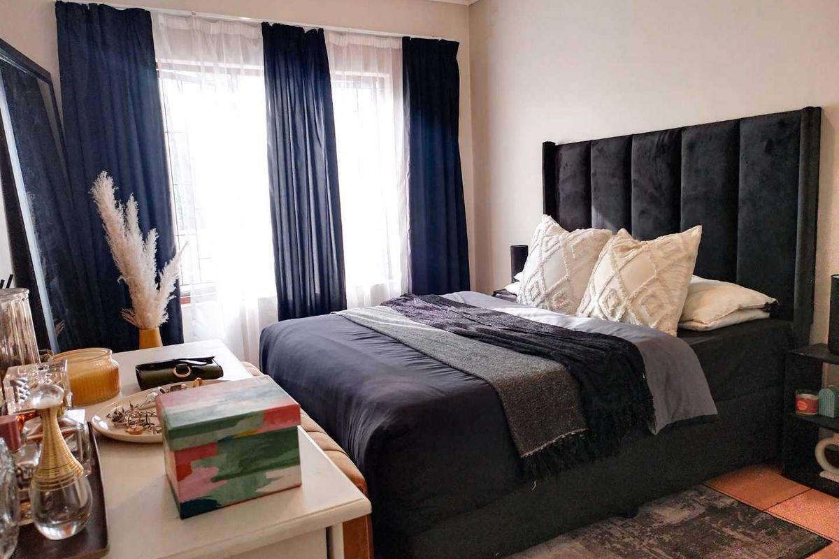 A well-maintained bedroom featuring a large window with curtain tracks and tiled flooring.