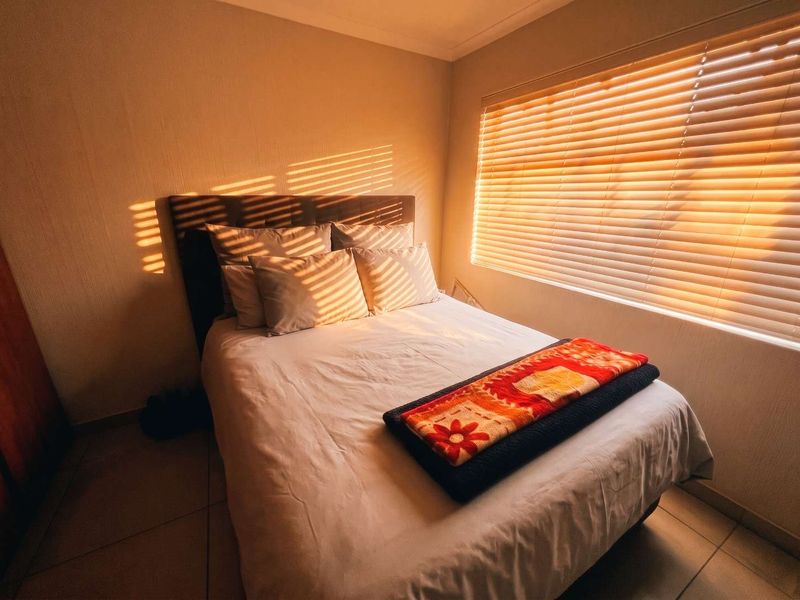 A cozy bedroom featuring tiled flooring, coved ceilings, and venetian blinds that allow for warm, natural light.