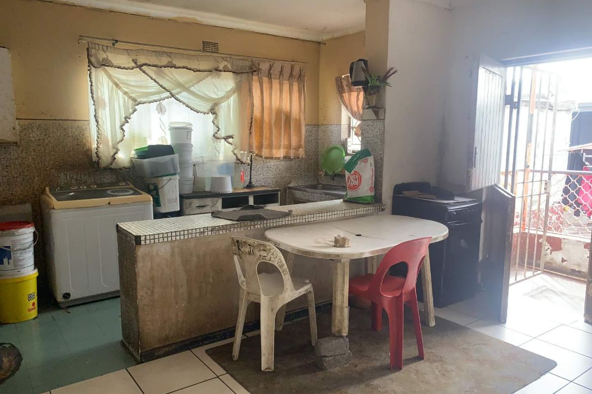 A dated kitchen area featuring a tiled breakfast bar, basic cabinetry, and direct access to an exterior entrance.