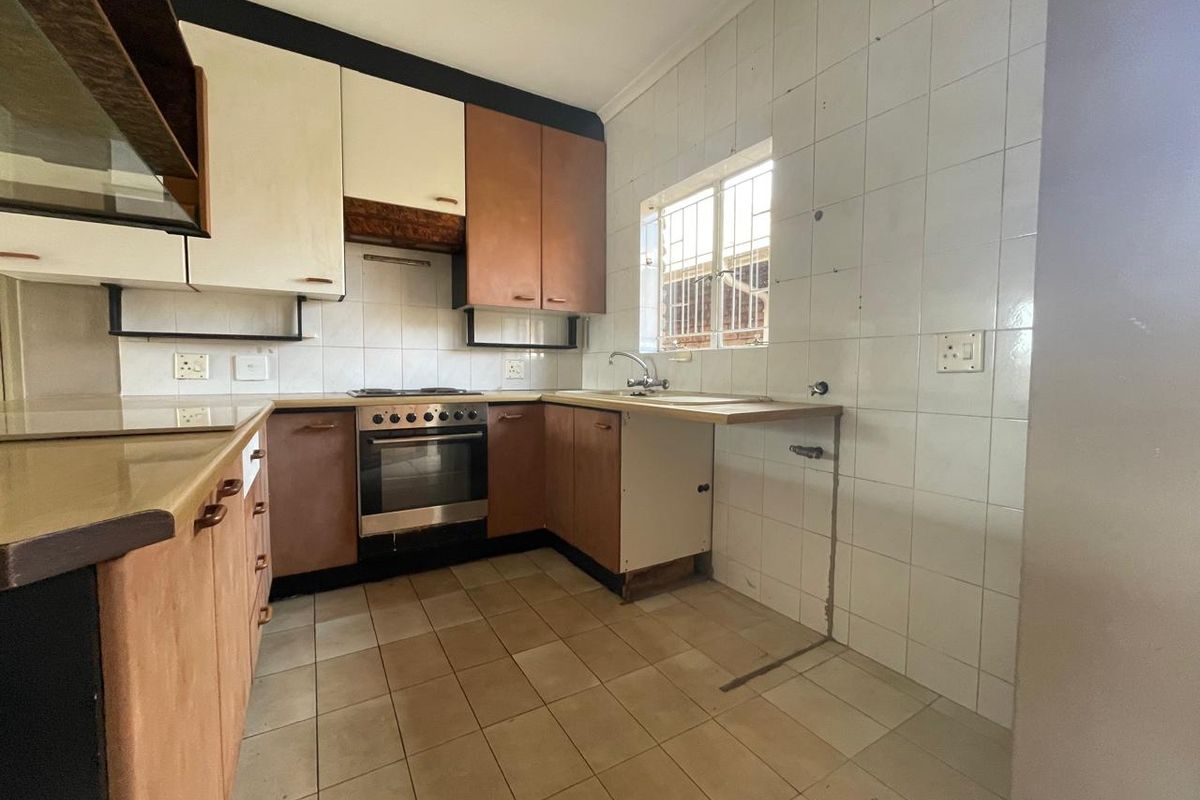 A dated kitchen featuring built-in cabinetry, an integrated oven and hob, tiled splashbacks, and tiled flooring, requiring cosmetic updates and repairs.