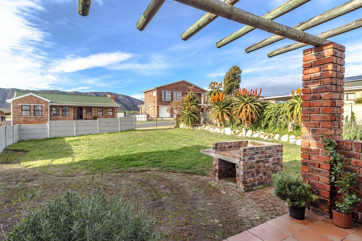 Rear garden featuring a brick paved patio, timber pergola, and a built-in brick braai area, offering a functional outdoor entertainment space.