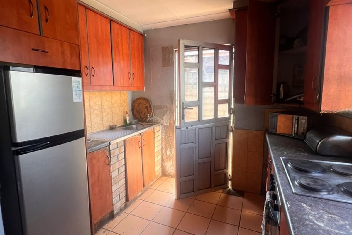 A functional kitchen featuring built-in cabinetry, tiled flooring, and a stable door leading to the exterior. The space would benefit from modern updates.