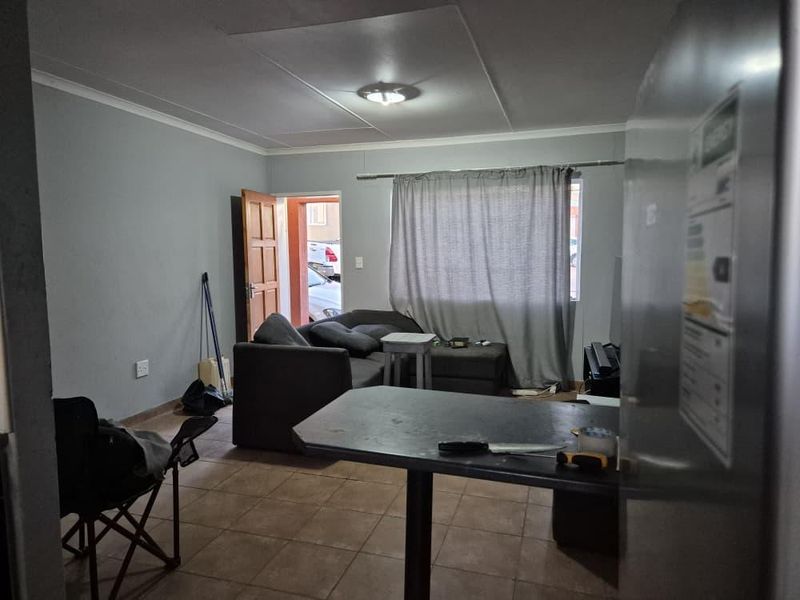 Open plan living area featuring tiled flooring and neutral wall tones, providing a functional space for combined living and dining arrangements.