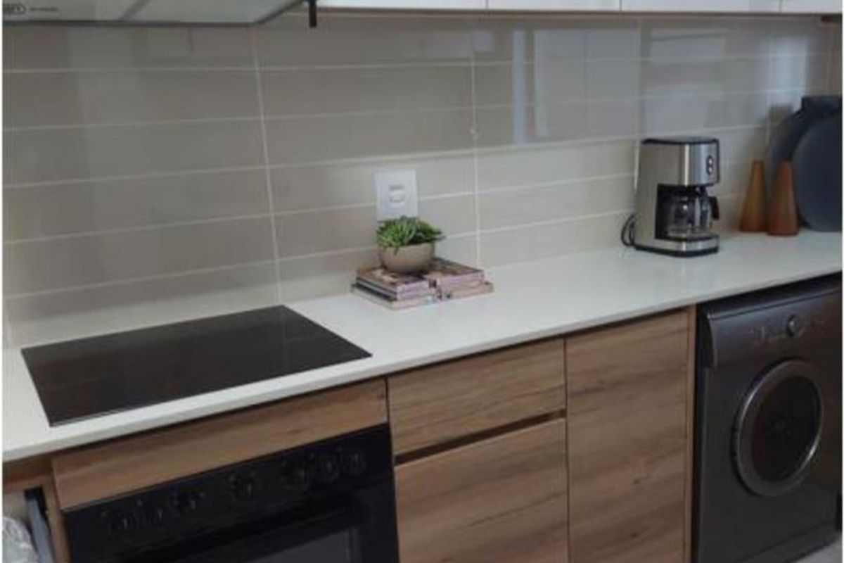 Modern kitchen featuring sleek two-tone cabinetry, stone countertops, built-in oven, electric hob, extractor fan, and integrated laundry appliance.