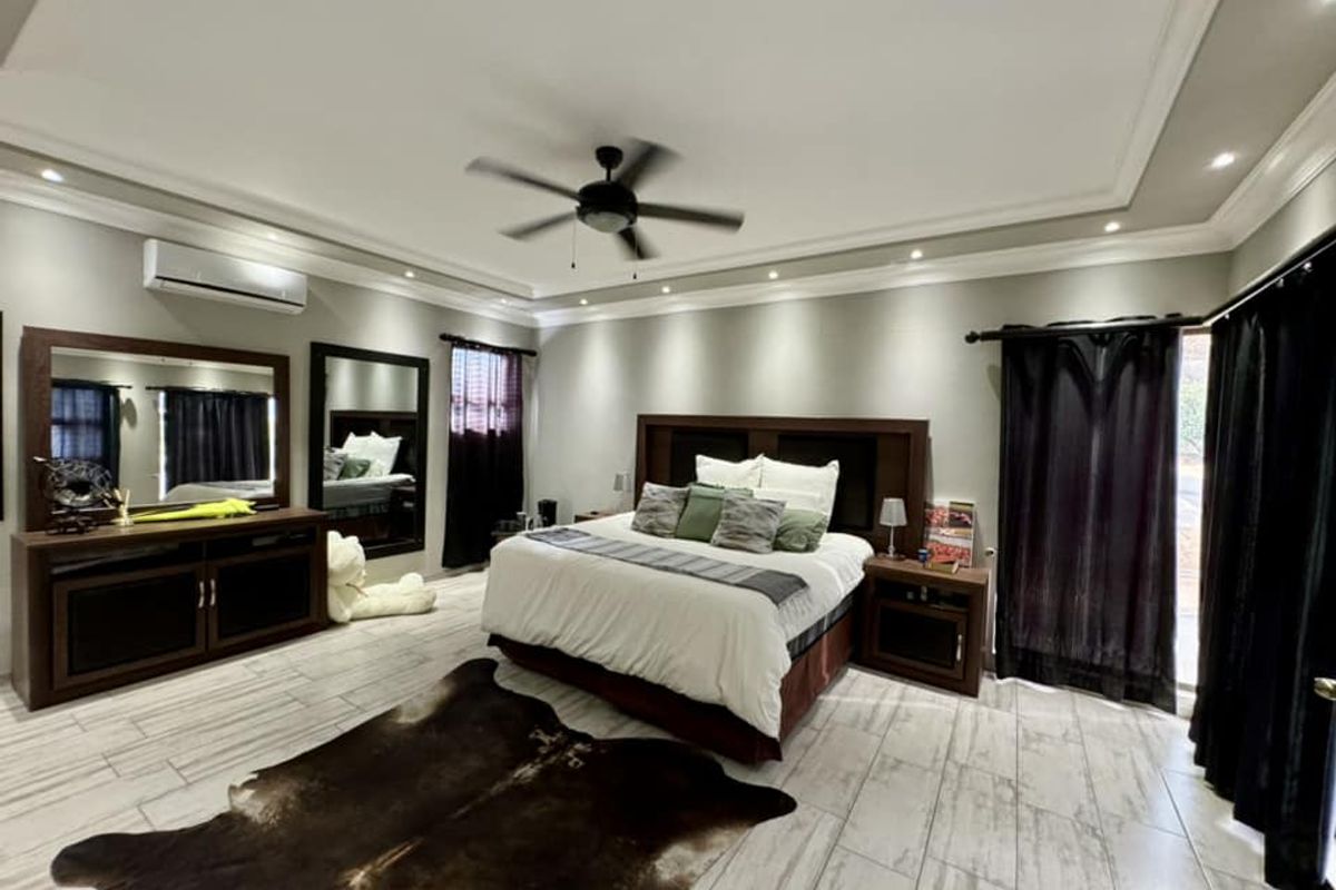 Spacious bedroom featuring tiled flooring, recessed ceiling lighting, a ceiling fan, and a wall-mounted air conditioning unit with direct access to the exterior.
