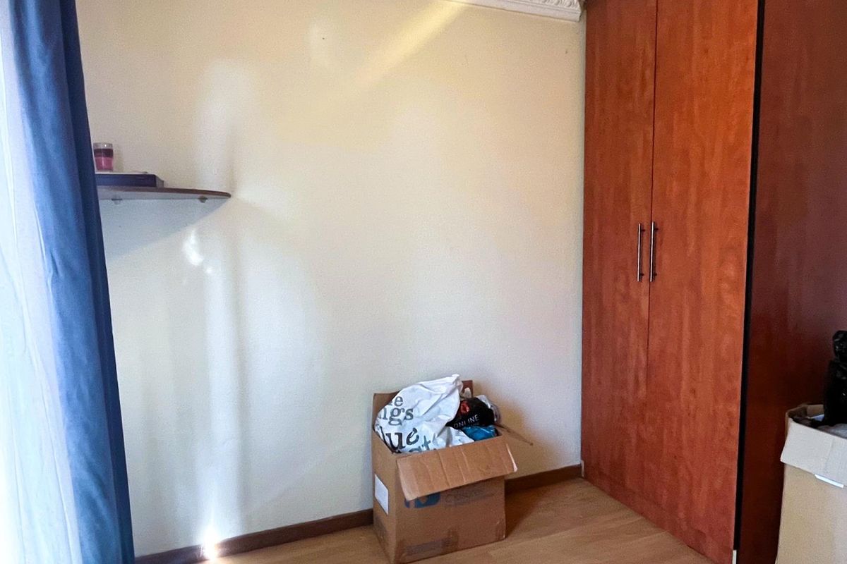 A bedroom featuring built-in wooden cabinetry and laminate flooring, providing functional storage space.