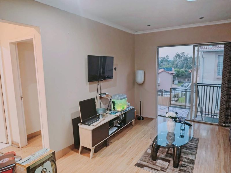 A living room featuring laminate flooring, recessed lighting, and a sliding glass door providing access to an outdoor balcony area.
