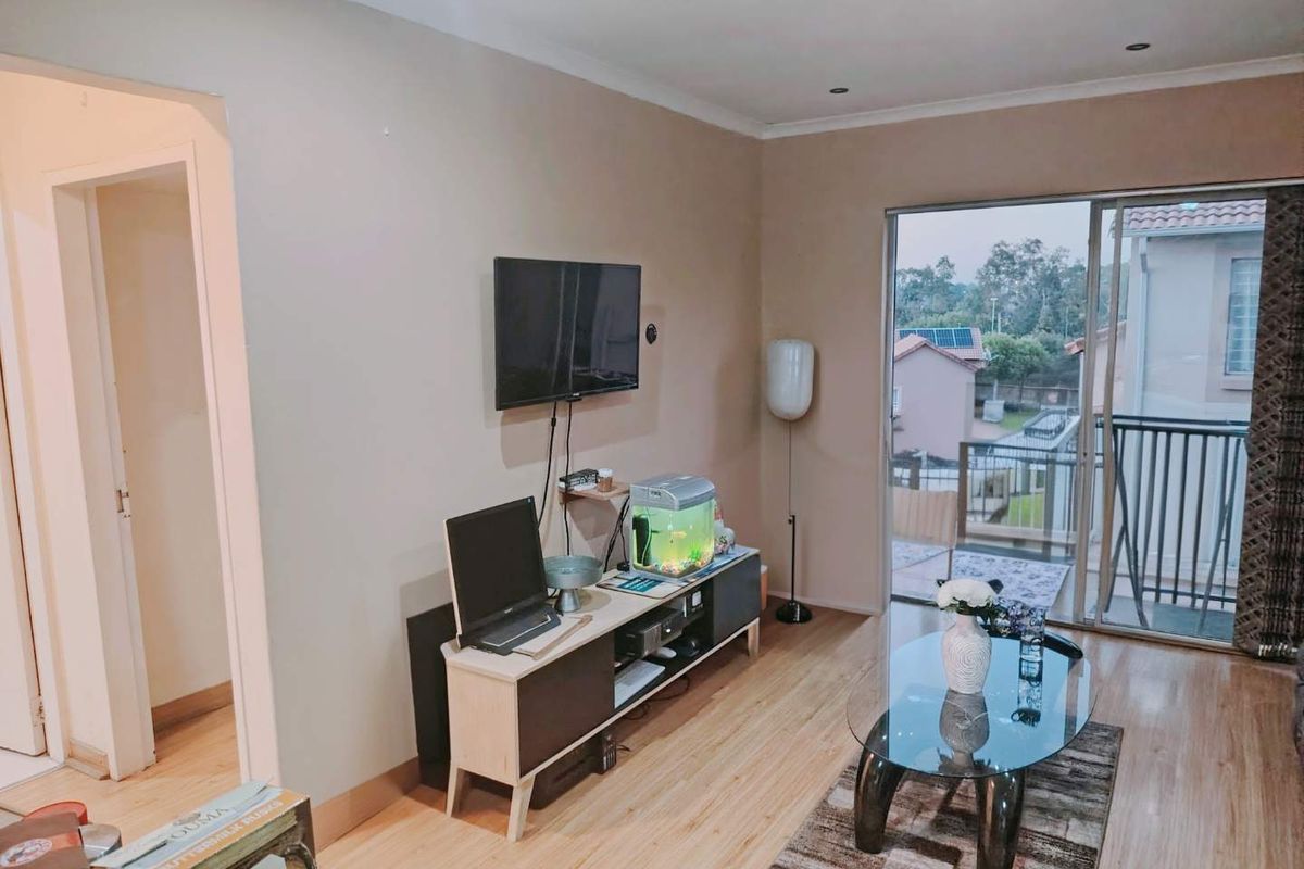 A living room featuring laminate flooring, recessed lighting, and a sliding glass door providing access to an outdoor balcony area.