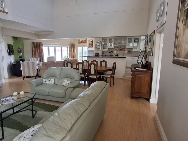 Spacious open-plan living and dining area featuring laminate flooring, a double-height ceiling, and a functional kitchen with built-in cabinetry.