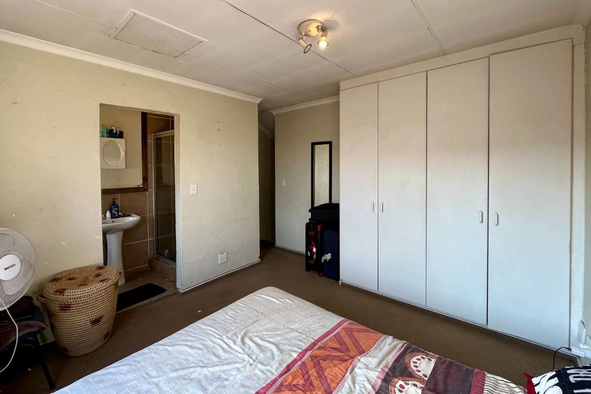 Bedroom featuring built-in wardrobes and an en-suite bathroom with a pedestal basin and shower enclosure.