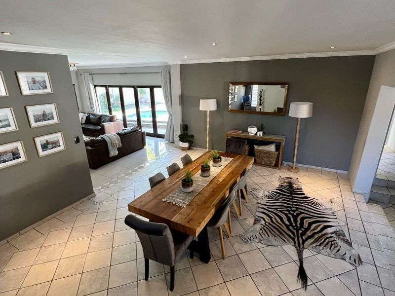 Spacious open-plan dining and living area featuring large format floor tiles, recessed lighting, and sliding glass doors leading to the outdoor pool area.