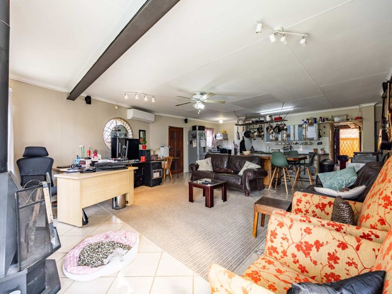 Spacious open-plan living area featuring a freestanding fireplace, ceiling fan, split-system air conditioning, and a functional kitchen with island seating.