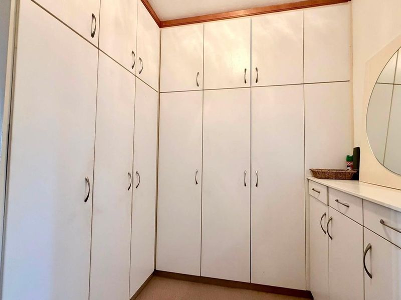 A bedroom featuring extensive floor-to-ceiling built-in cupboards and a fitted vanity unit with a mirror.