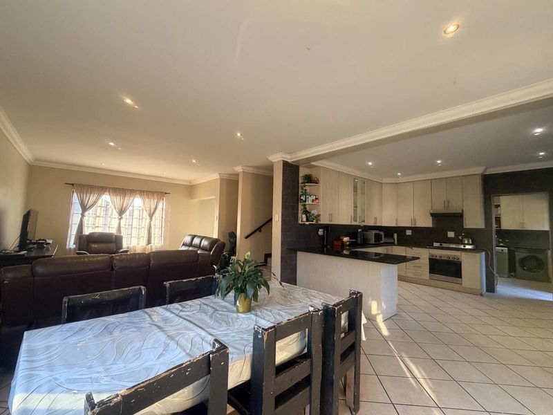 Open-plan living and dining area featuring a functional kitchen with granite countertops, built-in appliances, and tiled flooring throughout.