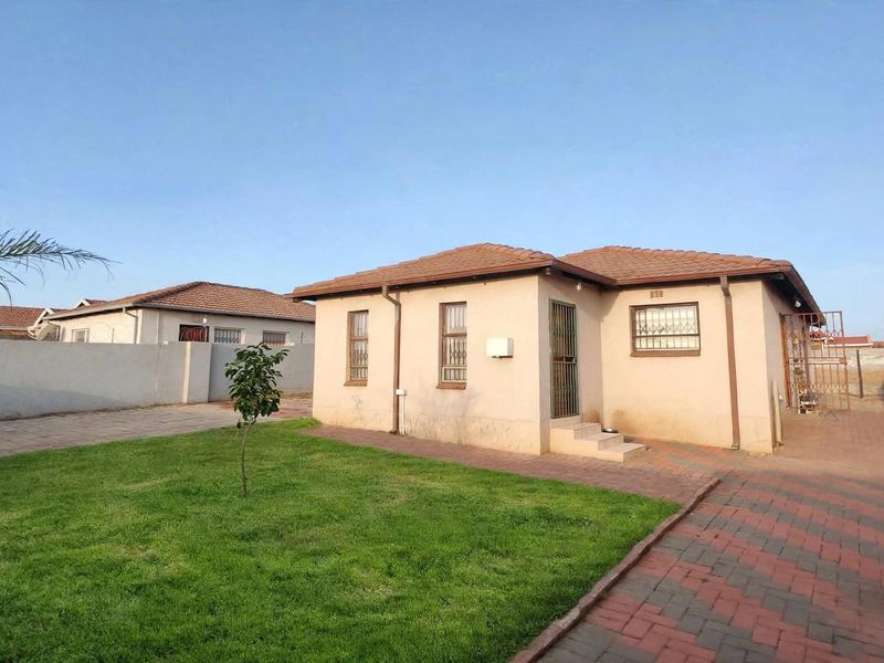 A detached single-story house featuring a tiled roof, paved driveway, and a well-maintained front lawn with boundary walling.