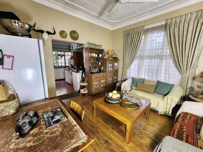 Open plan living area featuring original timber flooring and a decorative pressed metal ceiling, with an adjoining kitchen visible in the background.