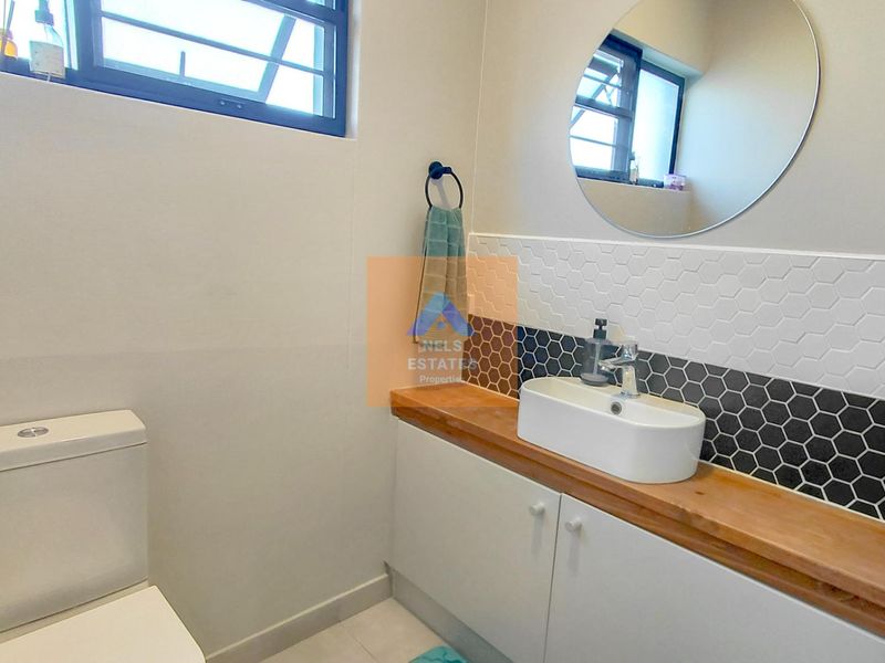 Modern bathroom featuring a vessel sink on a wooden vanity countertop, accented by a stylish black and white hexagon tile backsplash.