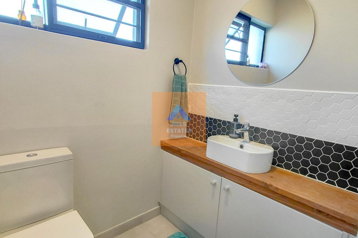 Modern bathroom featuring a vessel sink on a wooden vanity countertop, accented by a stylish black and white hexagon tile backsplash.