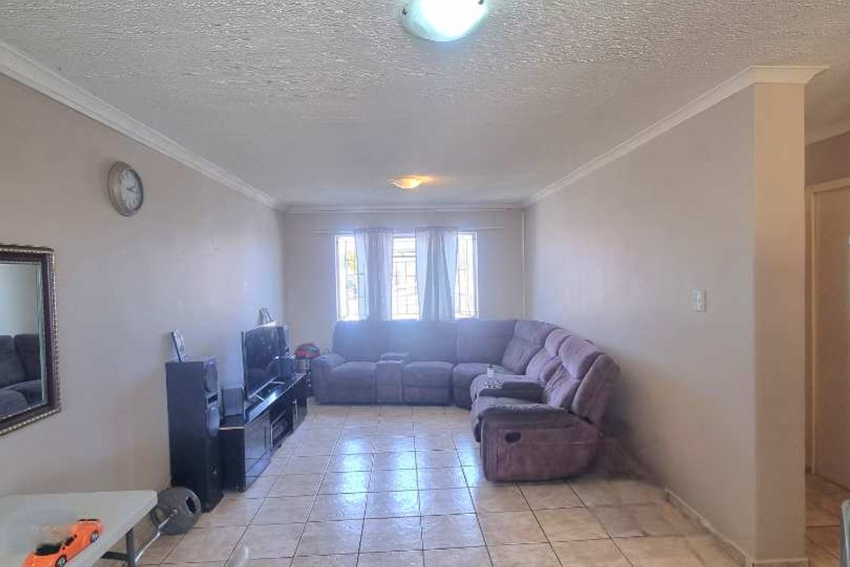 Spacious living area featuring neutral wall tones, tiled flooring, and a textured ceiling finish, providing a functional and open layout.