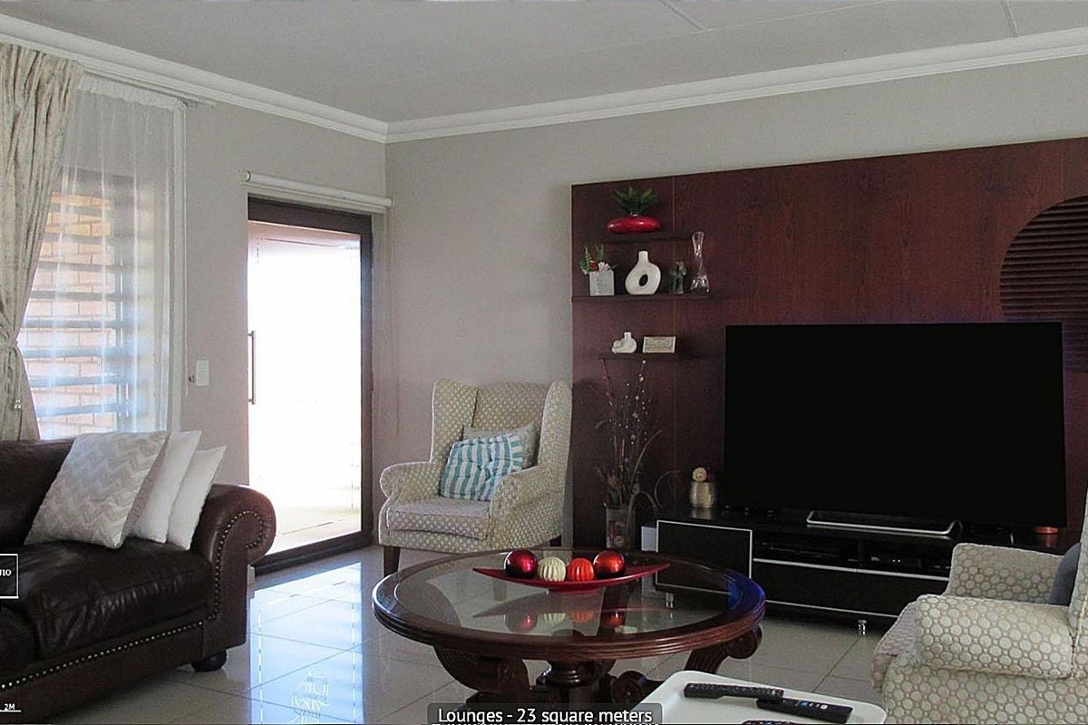Spacious living room featuring tiled flooring, a built-in wooden wall unit, and a sliding glass door providing access to the patio.