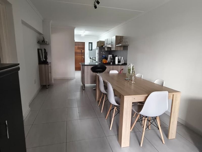 Open-plan living and dining area featuring tiled flooring and a functional kitchen with built-in cabinetry and island.