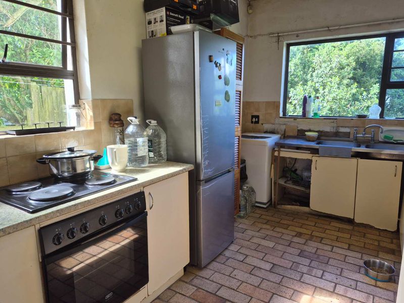 A functional kitchen space featuring a built-in oven, electric hob, and stainless steel sink, requiring cosmetic updates and cabinetry repairs to improve its overall condition.