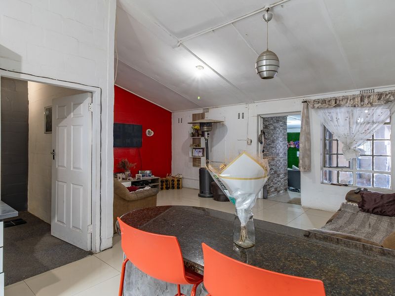 Open-plan living area featuring a granite breakfast counter, tiled flooring, and exposed beam ceilings, connecting to the kitchen and adjacent rooms.