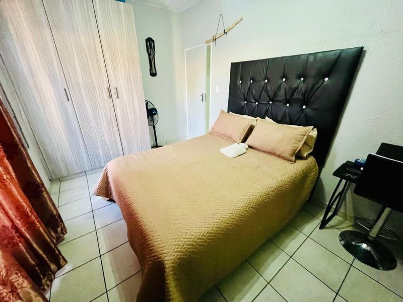 A functional bedroom featuring built-in cupboards and tiled flooring, providing a practical living space within the townhouse.