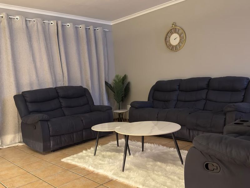 A comfortable living room featuring neutral wall tones, tiled flooring, and classic cove cornicing, providing a functional and inviting space for relaxation.