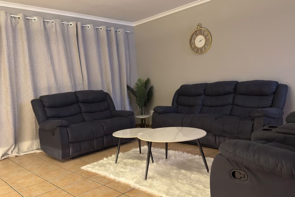 A comfortable living room featuring neutral wall tones, tiled flooring, and classic cove cornicing, providing a functional and inviting space for relaxation.