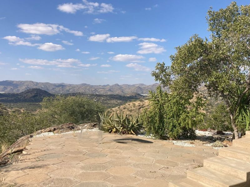 An elevated outdoor stone patio area featuring concrete steps and expansive, scenic views of the surrounding mountainous landscape.