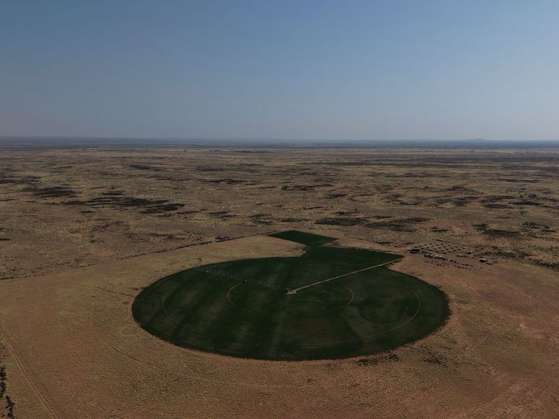 Aerial view of a large farm property featuring a circular irrigated crop field with a center pivot irrigation system.
