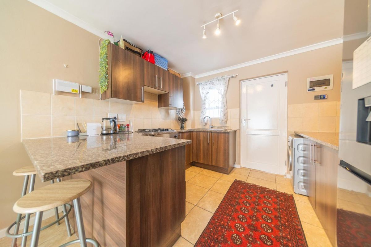 A functional kitchen featuring laminate cabinetry, granite countertops, tiled backsplash, and ceramic flooring, offering a practical layout with integrated hob and sink.