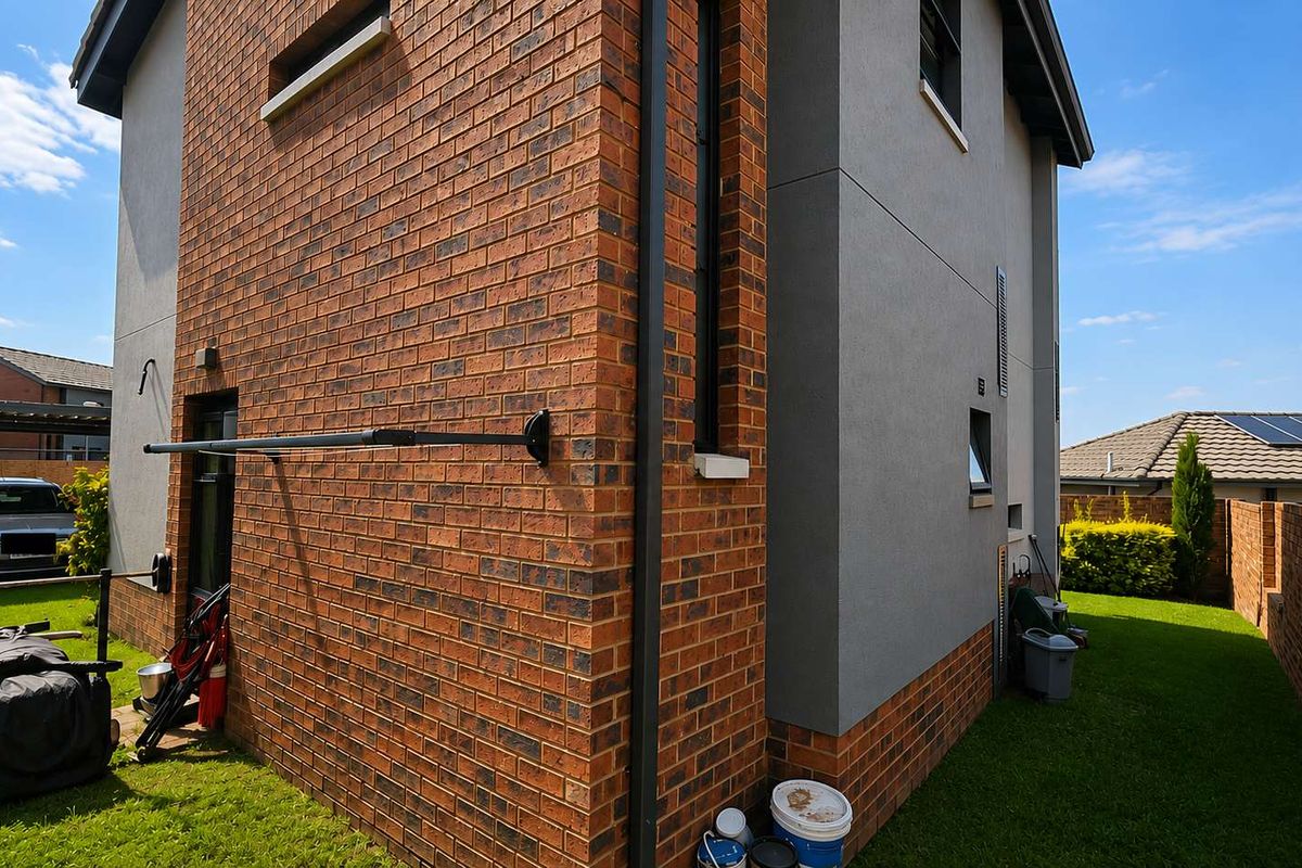 Side view of the property showing a combination of face brick and rendered exterior walls with a small lawn area.