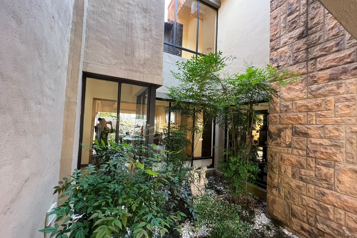 A private internal courtyard featuring stone cladding, large glass windows, and sliding doors that provide natural light to the surrounding interior spaces.