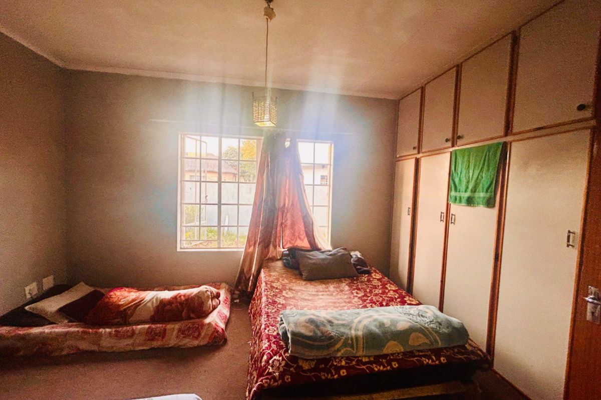 A bedroom featuring built-in floor-to-ceiling cupboards and a window providing natural light.