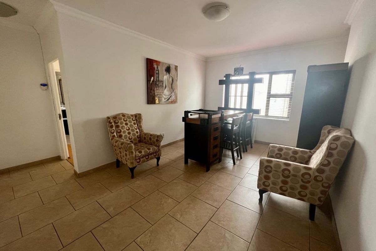 A living area featuring tiled flooring, a window with security bars, and access to an adjacent room.