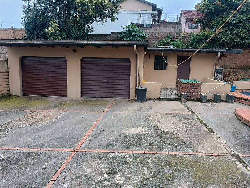 A double garage with roller doors and an adjacent concrete driveway area showing signs of wear and weathering.