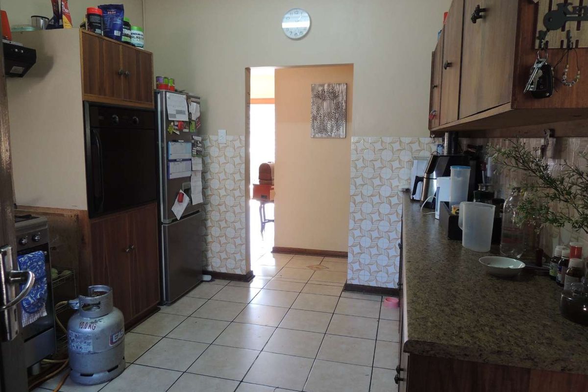A functional kitchen featuring tiled flooring, laminate cabinetry, and a built-in oven, offering a dated aesthetic ready for modernization.