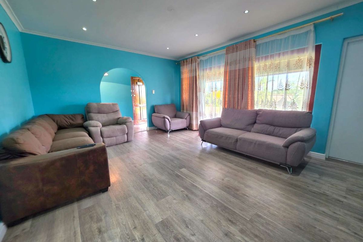 Spacious living room featuring modern wood-look laminate flooring, recessed ceiling lighting, and an arched doorway leading to an adjacent area.