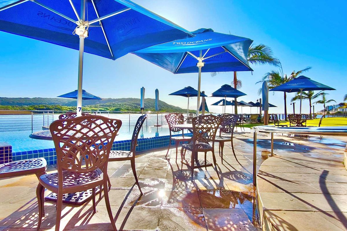 Outdoor pool area featuring stone paving, metal safety railings, and views of the surrounding landscape.