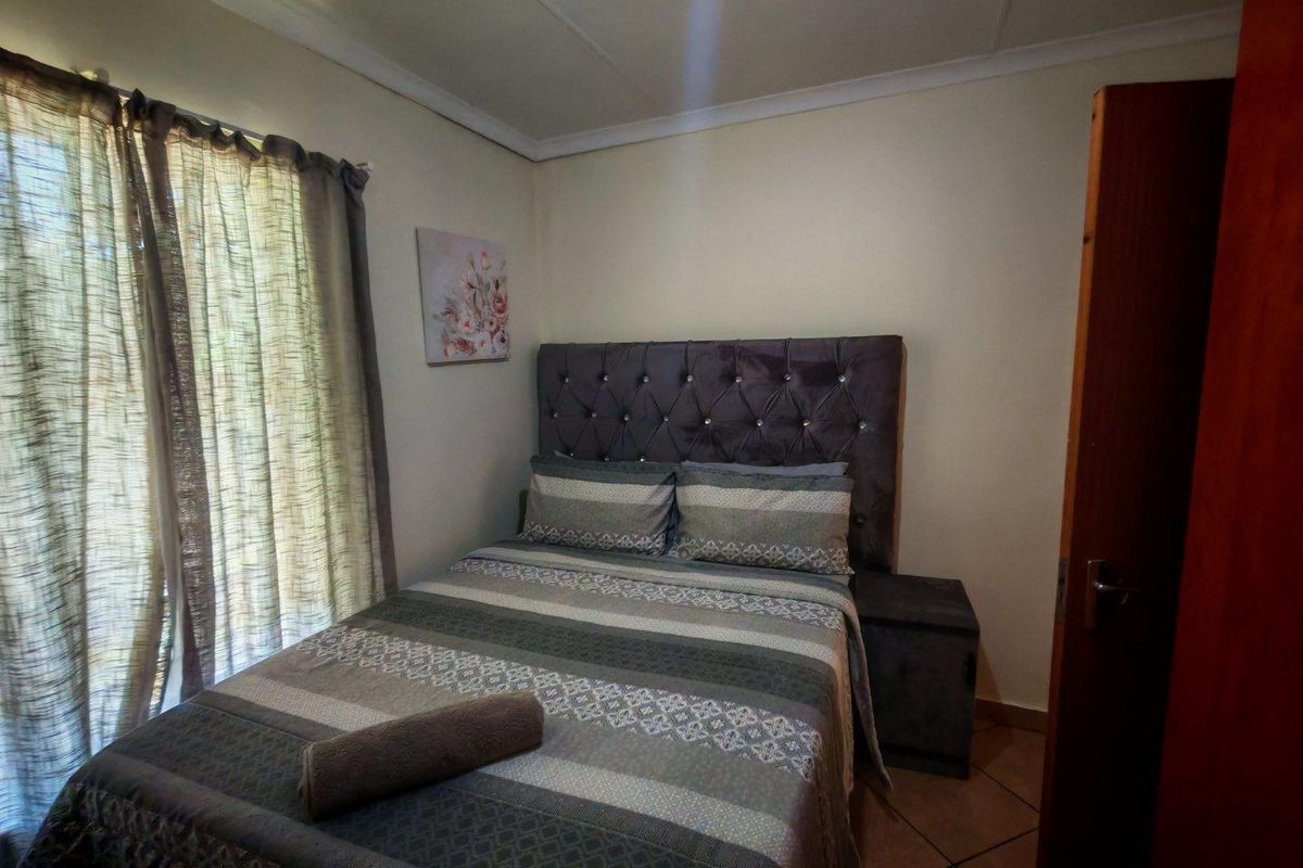 A cozy bedroom featuring tiled flooring and a window with curtains, providing a functional and comfortable sleeping space.