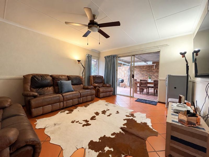 A comfortable living room featuring tiled flooring, a ceiling fan, and sliding glass doors that provide direct access to an outdoor patio area.