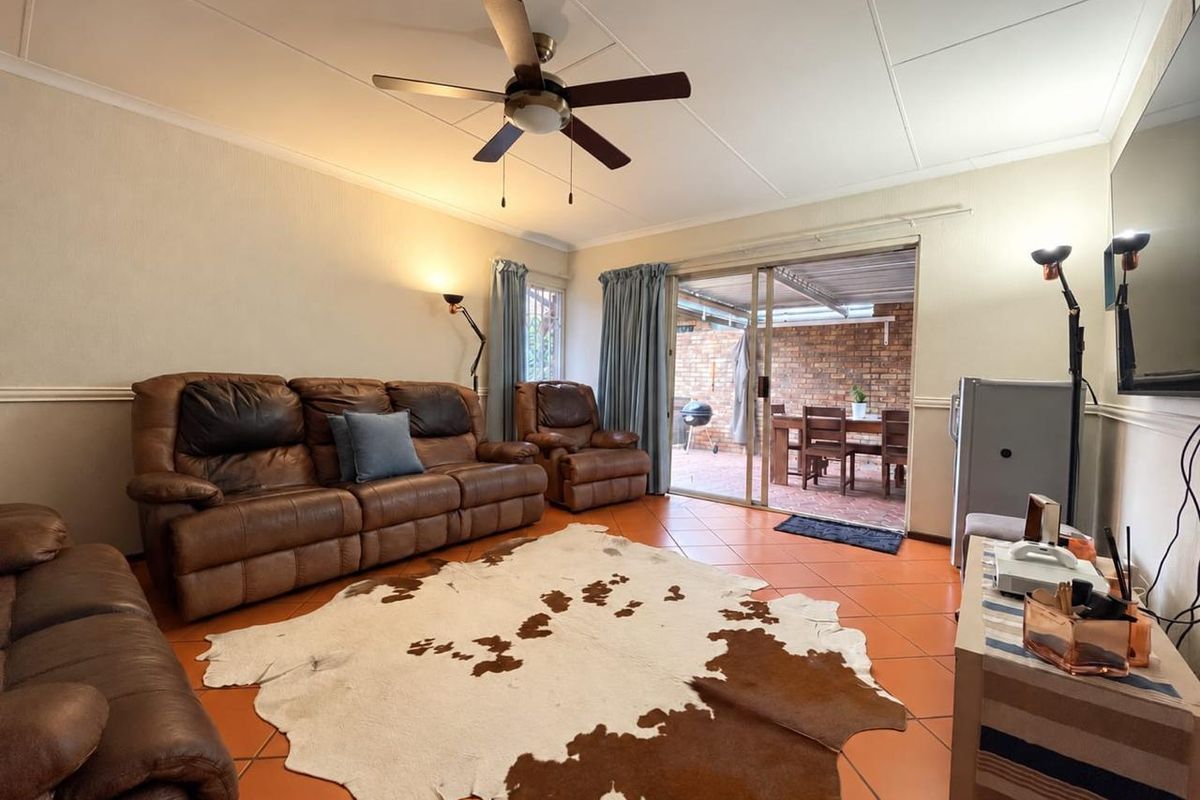 A comfortable living room featuring tiled flooring, a ceiling fan, and sliding glass doors that provide direct access to an outdoor patio area.