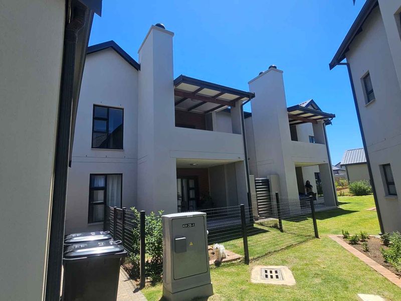 Rear view of modern apartment units featuring covered patios with timber pergolas, chimneys, and well-maintained garden spaces with paved walkways.