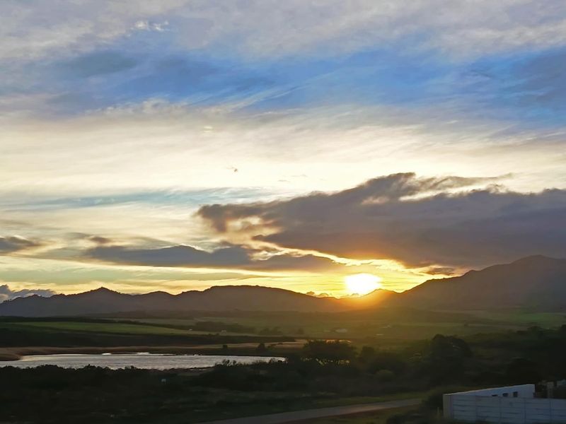 A scenic sunset view overlooking the natural landscape, featuring rolling hills and a tranquil water body.
