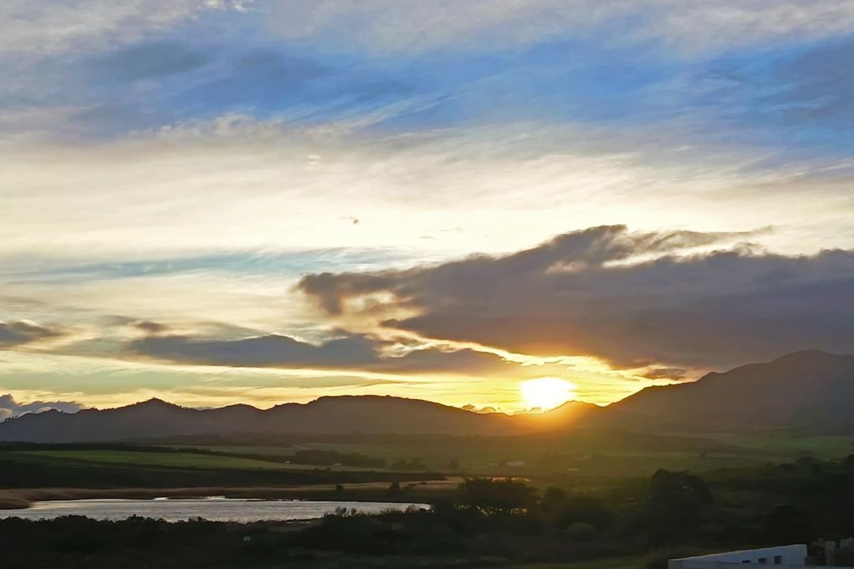 A scenic sunset view overlooking the natural landscape, featuring rolling hills and a tranquil water body.