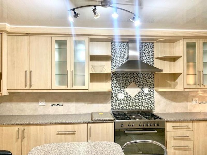 A well-maintained kitchen featuring light-wood cabinetry, granite countertops, a mosaic tile backsplash, and integrated stainless steel cooking appliances.